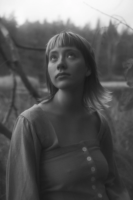 A black and white photo of lupina standing in a forest looking at the sky.